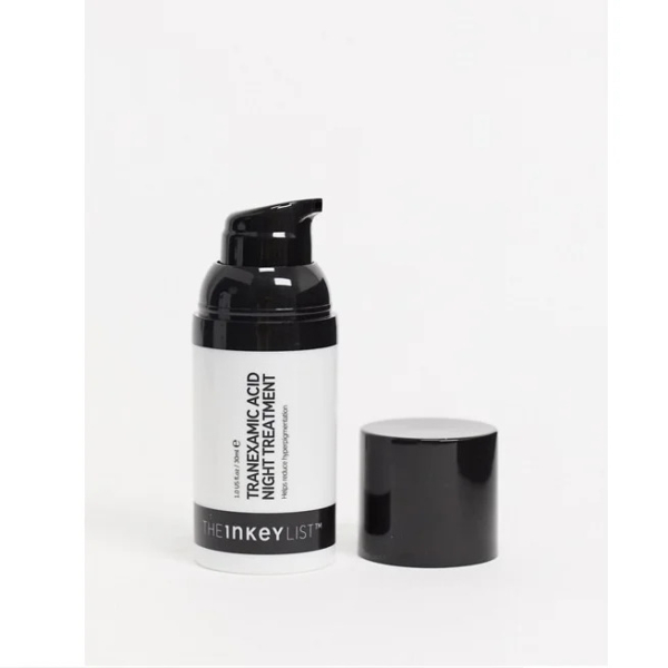 Une bouteille blanche de traitement de nuit à l'acide tranexamique de The Inkey List avec un distributeur à pompe noir est présentée avec son bouchon noir placé à côté. Dakar