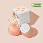 Le pot ouvert de 20 ml du Masque de Nuit à lèvres Vita Glazed de Tocobo, couleur pêche, avec son applicateur, souligne l'élégance de LANEIGE. Le coffret arbore des motifs floraux colorés et le logo « Eve Vegan » vert sur fond rose clair. Dakar