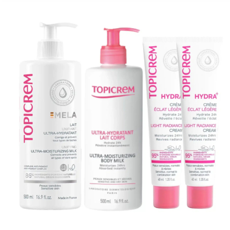 Quatre produits de soin Topicrem sont présentés : le Lait Corps Ultra-Hydratant, le Lait Ultra-Hydratant MELA et deux crèmes Hydra+ Légère Éclat. Les flacons et tubes, aux touches de rose, sont étiquetés pour l'hydratation et les peaux sensibles. Dakar