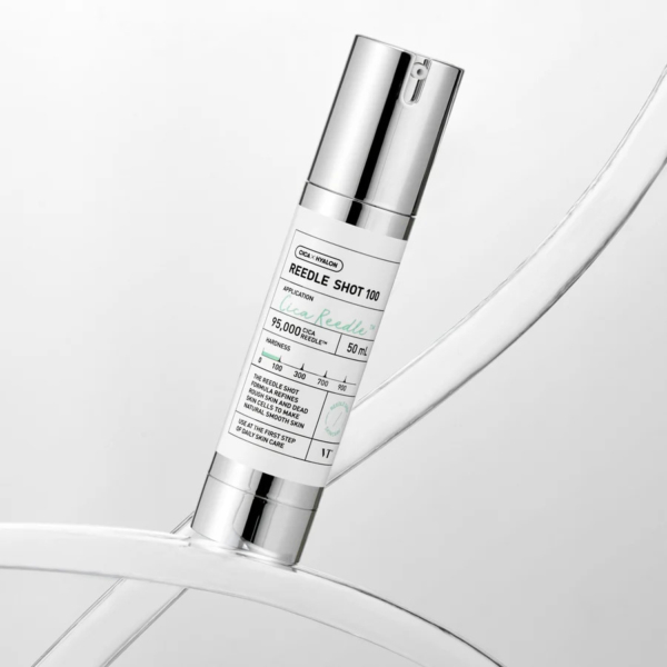 Une bouteille cylindrique de « REEDLE SHOT » de Needly, étiquetée comme contenant 50 ml et contenant du thé vert. La bouteille est métallique, avec des touches de blanc et de vert menthe, et se détache sur un fond clair et abstrait. Dakar