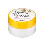Un petit récipient rond au couvercle jaune, étiqueté « Honey & Milk Lip Sleeping Pack », par A'Pieu. Le couvercle est décoré de dessins d'abeille, de miel et de lait. Le fond du récipient est blanc. Dakar
