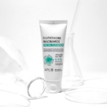 Un tube blanc de « Aplb Glutathione Niacinamide Nettoyant Doux 80 ml » se dresse au milieu de verrerie de laboratoire transparente sur un fond blanc, créant une atmosphère propre et clinique. Dakar