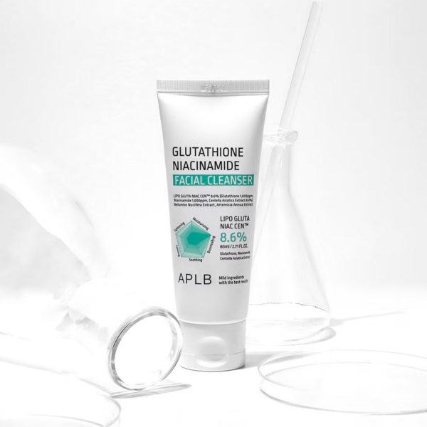 Un tube blanc de « Aplb Glutathione Niacinamide Nettoyant Doux 80 ml » se dresse au milieu de verrerie de laboratoire transparente sur un fond blanc, créant une atmosphère propre et clinique. Dakar