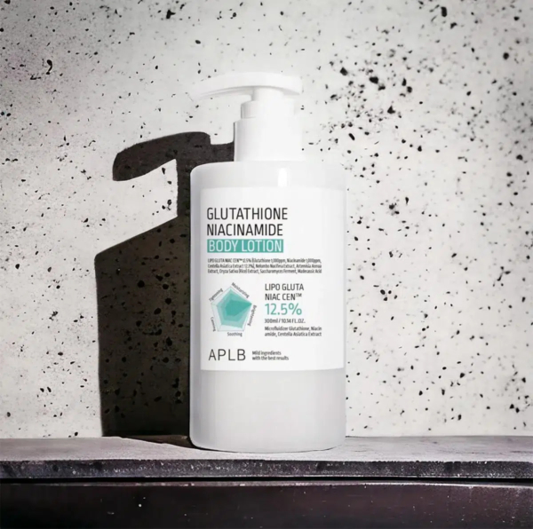 Un flacon blanc de lotion corporelle au glutathion et à la niacinamide, muni d'une pompe, se détache sur un fond gris moucheté. L'étiquette détaille les ingrédients et la concentration de la lotion, avec notamment les mentions « LIPPO Gluta » et « 12,5 % ». Dakar