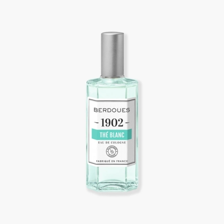 Un flacon en verre transparent de BERDOUES 1902 L'Eau de Cologne Blanche, orné d'un bouchon argenté et étiqueté en blanc avec un texte noir et vert, met en valeur avec élégance son charme sur un fond clair, évoquant une essence intemporelle. Dakar