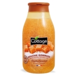 Un flacon orange de 270 ml de Cottage Douche Gommage Exfoliant Tendre Caramel, avec des morceaux de caramel et un bouchon à rabat marron, offre un gel douche exfoliant au doux parfum de caramel. Dakar