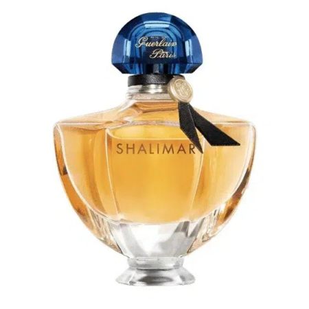 Un flacon de parfum étiqueté « Shalimar » au design élégant et facetté. Il contient un liquide ambré et est doté d'un bouchon bleu bombé et d'un ruban noir décoratif autour du col. Dakar
