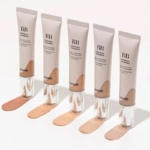 Cinq tubes de BB crème, étiquetés « Moringa Ceramide », sont alignés. Chaque tube distribue une teinte différente sur une surface blanche, présentant un dégradé de tons clairs à foncés. Les tubes portent la marque « Heimish ». Dakar