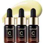 Trois flacons en verre foncé avec compte-gouttes dorés, étiquetés « Medicube Deep Vita C Ampoule 14,5% », sont alignés sur une tache jaune clair du produit, une correspondance parfaite avec l'éclat radieux du Medicube Sérum Éclaircissant Avancé Vitamine C Pure x10 ml. Dakar