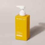 Un flacon jaune de Medix 5.5 Gel Douche à la Vitamine C et à la Niacinamide 444 ml avec une pompe blanche repose sur une surface claire, projetant une ombre vers la droite. Dakar