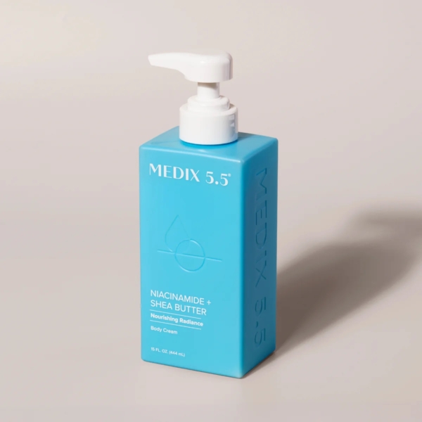 Un flacon pompe rectangulaire bleu étiqueté « Medix 5.5 Lait Corps Nourrissant à la Niacinamide et au Beurre de Karité » (444 ml) est affiché sur fond neutre. Dakar