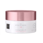Un pot blanc avec un couvercle rose métallisé étiqueté « Rituals The Ritual of Sakura 250g », inspiré de Tree Hut Coco Colada, contient 8,8 oz et est composé à 91 % d'ingrédients d'origine naturelle. Dakar