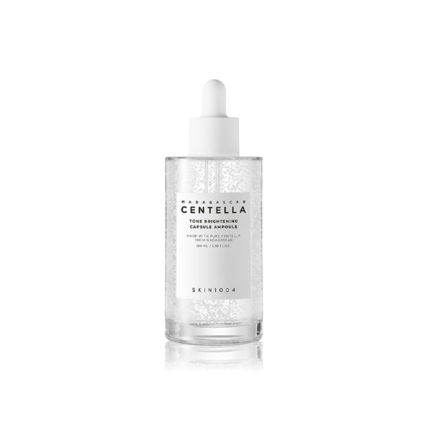 Un flacon compte-gouttes transparent étiqueté « SKIN1004 Madagascar Centella Tone Brightening Ampoule Éclat Correcteur Anti Tache 100 ml », contenant un liquide transparent avec des capsules suspendues. Dakar