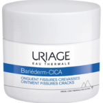 Un pot blanc portant l'inscription « Uriage Eau Thermale Bariéderm-CICA ». Le texte indique qu'il s'agit d'un onguent pour les fissures et les crevasses. Le pot est orné d'une bande bleue et d'un motif de montagne au fond. Dakar