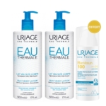 Deux flacons de Lait Corps Soyeux Uriage Eau Thermale, pompes bleues, de 500 ml chacun, sont placés à côté d'un flacon plus petit de 50 ml de crème solaire Uriage Bariésun SPF 100. Une étiquette dorée « OFFERT » est apposée sur la crème solaire, indiquant qu'elle est offerte. Dakar