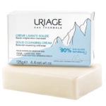 Un pain de savon solide nettoyant Uriage Eau Thermale de 125 g est présenté. Son emballage, orné d'un motif montagne, souligne sa composition 90 % naturelle et son adaptation aux peaux sensibles du visage et du corps. Dakar