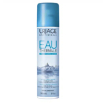Un vaporisateur Uriage Eau Thermale de 300 ml avec un bouchon bleu. L'étiquette représente une montagne et de l'eau, soulignant sa teneur en eau thermale. Le texte sur le flacon indique qu'il est hypoallergénique et sans parfum. Dakar