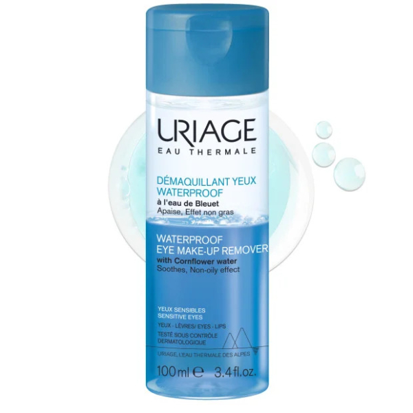 Flacon de Démaquillant Yeux Waterproof Uriage avec bouchon et étiquette bleus. Un texte en français et en anglais décrit ses effets apaisants et non gras à l'eau de bleuet, adaptés aux yeux sensibles. Contenance : 100 ml. Dakar