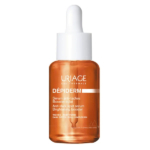 Un flacon de sérum Uriage Dépiderm avec compte-gouttes. L'étiquette indique « Sérum anti-taches, Booster d'éclat » pour traiter les taches brunes et le teint terne. Le flacon est de couleur ambrée avec un texte blanc. Dakar