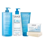 Une collection de soins Uriage comprenant un grand flacon pompe de gel dermatologique, un flacon de lait corporel, un tube de crème exfoliante et un pain de savon nettoyant. Tous les articles sont dotés d'étiquettes bleues et blanches. Dakar