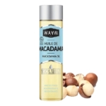 Une bouteille d'huile de macadamia au bouchon argenté, étiquetée « Huile de Macadamia » et « 100 % Pure Végétale », se trouve à côté d'un amas de noix de macadamia décortiquées et non décortiquées. L'étiquette est principalement bleu clair. Dakar