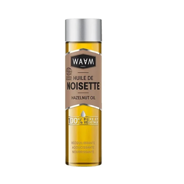 Un flacon d'huile de noisette WAAM au bouchon argenté et au corps transparent. L'étiquette porte les inscriptions « Huile de Noisette » et « Huile de Noisette », soulignant sa pureté « 100 % Pure et Végétale ». Elle souligne ses vertus équilibrantes, adoucissantes et nourrissantes. Dakar