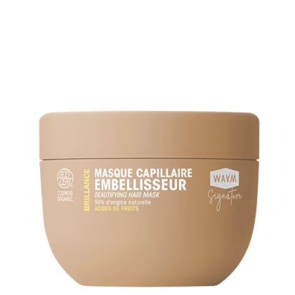 Un contenant beige portant l'inscription « Masque capillaire sublimateur Brilliance » en blanc et jaune. L'étiquette indique « 99 % d'origine naturelle », le logo « Cosmos Organic » et la marque « WAVM Signature ». Le contenant est doté d'un couvercle rond et plat. Dakar