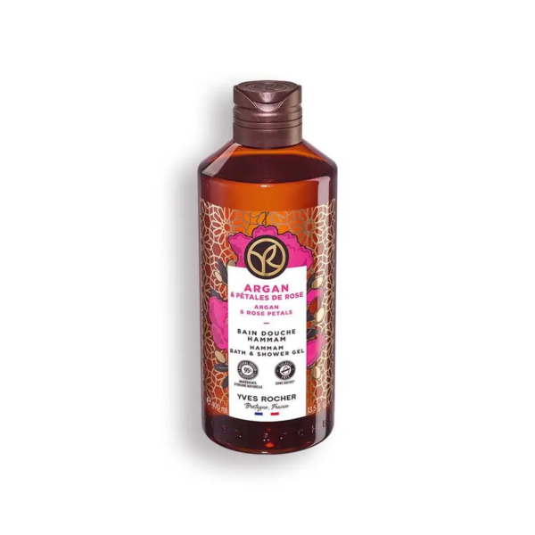 Un flacon de gel douche Yves Rocher Argan et Pétales de Rose. Le flacon marron arbore une étiquette rose et dorée ornée de motifs floraux et d'un texte détaillant les ingrédients et le nom de la marque. Dakar