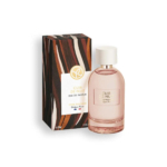 Un flacon d'Eau de Parfum « Cuir de Nuit » est posé à côté de son écrin. Le flacon, de forme ronde et transparente, est coiffé d'un bouchon blanc. L'écrin arbore un motif ondulé marron et noir. Dakar