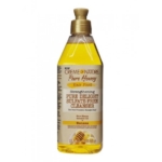 Un flacon de 355 ml de Crème of Nature Pure Honey Nettoyant Fortifiant-et-Réparateur (Cleanser Banana) pour cheveux secs et abîmés. Flacon transparent avec liquide jaune, bouchon à pression et étiquette à l'effigie de banane, de miel et d'huile de coco. Dakar