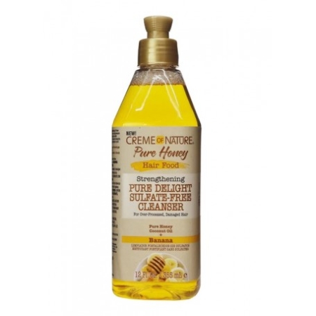 Un flacon de 355 ml de Crème of Nature Pure Honey Nettoyant Fortifiant-et-Réparateur (Cleanser Banana) pour cheveux secs et abîmés. Flacon transparent avec liquide jaune, bouchon à pression et étiquette à l'effigie de banane, de miel et d'huile de coco. Dakar