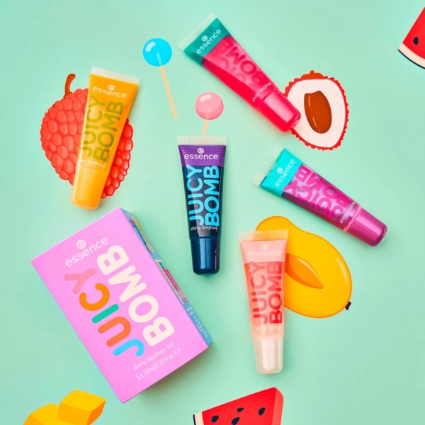 Coffret d'Huiles pour Lèvres 02 Sweet And Glossy! de Five Essence Cosmetics Juicy Bomb 5 huiles pour lèvres de 2,4 ml sont disposées sur une surface à motifs de fruits bleu sarcelle, avec une boîte rose assortie sur le côté, créant un affichage ludique et fruité. Dakar