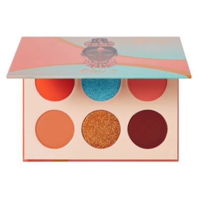 La Palette de Fards à Paupières Olori III de Juvias Place présente six teintes audacieuses - orange, bleu, rouge, beige, paillettes dorées et bordeaux - dans un étui pêche avec un visage illustré sur le couvercle. Dakar