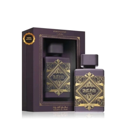 Un flacon violet de Lattafa Badee Al Oud Ametyst Eau de Parfum pour femme 100ml se trouve à côté de son coffret décoratif assorti, tous deux ornés de motifs géométriques dorés et d'un texte bilingue en anglais et en arabe. Dakar