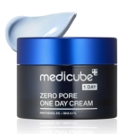 Un pot bleu et noir de crème de jour Medicube Zero Pore, sans couvercle, présente une crème bleu clair. L'étiquette indique 5 % de panthénol et 0,1 % de BHA, et s'accorde parfaitement avec les tampons exfoliants Medicube Zero Pore Pad 2.0, anti-pores dilatés et anti-acné (70 tampons). Dakar