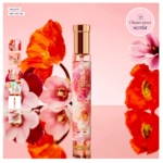 Un flacon d'Eau de parfum pailletée Adopt Bouquet d'Amour 30 ml au bouchon doré repose sur une surface réfléchissante rose, au milieu de grandes fleurs rouges et roses. De petites images du produit sont visibles à gauche, et « Cliquez pour sentir » est indiqué en haut à droite. Dakar