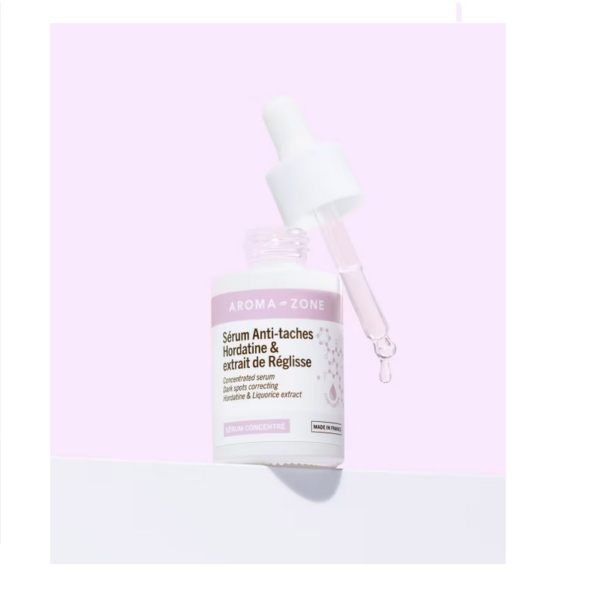 Aroma Zone Sérum Anti-taches Hordatine et Extrait de Réglisse 30 ml avec compte-gouttes se dresse sur un fond rose pastel, une goutte scintillante à la pointe. Dakar