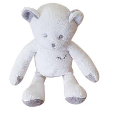 Le Doudou Mustela est un ours en peluche blanc et doux, avec des accents gris clair sur les oreilles, les pattes et les pieds. Il est représenté en position assise sur un fond blanc. Dakar