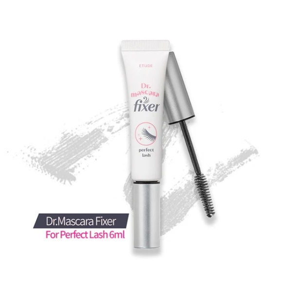 Un tube de Mascara Gel Fixateur Transparent Etude Dr 6 g avec son applicateur baguette exposé à côté, sur un fond clair avec un coup de pinceau de mascara derrière. Dakar