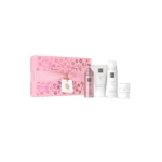 Un coffret cadeau rose sur le thème des fleurs de cerisier, The Ritual of Sakura Coffret ressourçant, avec un nœud et quatre produits pour le bain et le corps - un vaporisateur rose et trois flacons/jarres blancs - disposés proprement sur un fond blanc. Dakar