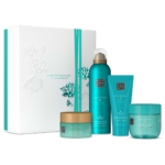 Un ensemble de quatre produits de soins corporels Rituals Coffret Moyen Le Rituel du Karma en sarcelle et or, présentés dans un coffret cadeau floral blanc rehaussé de sarcelle. Le texte de la boîte est le suivant : "Une vie remplie d'émerveillement est une vie merveilleuse. Dakar