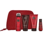 Le Coffret Cadeau Rituals The Ritual Of Ayurveda comprend une trousse de toilette rouge avec quatre produits - gel douche moussant, shampoing, après-shampoing et huile pour le corps - dans des flacons et des tubes rouges et bruns disposés devant la trousse. Dakar