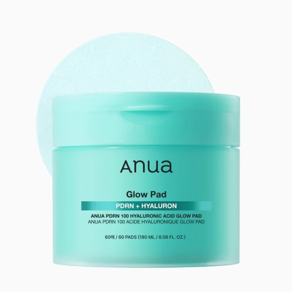 Un contenant turquoise d'Anua PDRN Hydratant Éclat Visage Anti Age 100 Hyaluronic Acid Glow contient 60 tampons de soin ronds, visibles avec le couvercle partiellement ouvert. L'étiquette met en évidence l'acide hyaluronique et le nombre total de tampons. Dakar