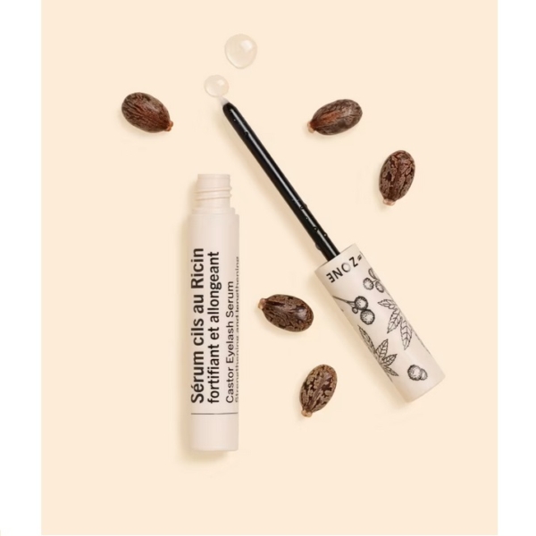 Un tube ouvert d'Aroma Zone Sérum Cils Fortifiant Au Ricin Bio 6ml avec un pinceau applicateur, étiqueté en français, trône parmi des graines de ricin sur un fond beige, évoquant The Ordinary Sérum. Dakar