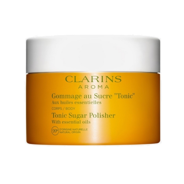 Un pot d'Aroma Gommage Corps au Sucre Tonic aux Huiles Essentielles 250 ml de Clarins pour le soin du corps, présenté dans une boîte orange et blanche avec les détails du produit en français et en anglais. Dakar