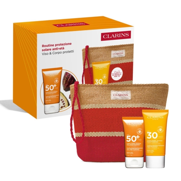 Le Coffret Clarins comprend la Crème Solaire Visage SPF50 (50ml), la Crème Solaire Corps SPF30 (75ml) et une pochette tressée rayée rouge et beige, le tout présenté dans une boîte orange avec des informations et des images sur le produit. Dakar