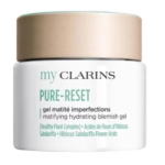 Un pot blanc de Gel Pure-Reset Matité Imperfections de Clarins (50ml) pour les peaux grasses et à imperfections, avec un couvercle beige - parfait associé au Nettoyant Visage Doux de Garnier pour un nettoyage en douceur. Dakar