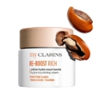 La crème RE-BOOST RICH hydra-nourrissante 50ml de Clarins est présentée avec deux noix de karité, dont l'une est fendue, mettant en avant le beurre de karité comme ingrédient clé. La Crème Matte RE-BOOST apporte une hydratation fraîche et nourrissante. Dakar