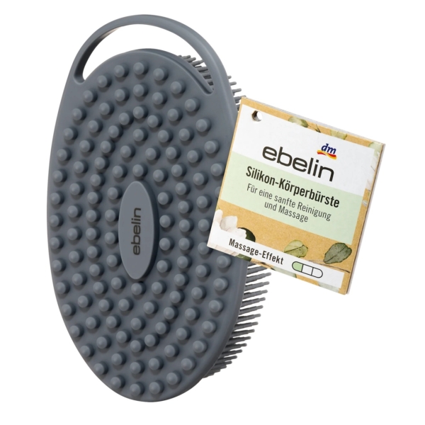 La Brosse Corporelle en Silicone 1 pièce d'Ebelin est une brosse corporelle ovale en silicone de couleur grise avec des poils courts et un manche, présentée à côté de son emballage pour un nettoyage et un massage en douceur. Dakar