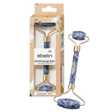 Le Rouleau de Massage Facial Ebelin en Feldspath Sodalite Bleu 1 pièce présente un rouleau marbré bleu et blanc avec des accents dorés, montré à l'intérieur et à l'extérieur de sa boîte ebelin florale avec une fenêtre transparente et le texte du produit en allemand. Dakar